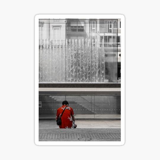 Discover A man in a red shirt sits in front of a fountain